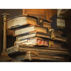 an old stack of books sitting on top of a wooden table next to a lamp