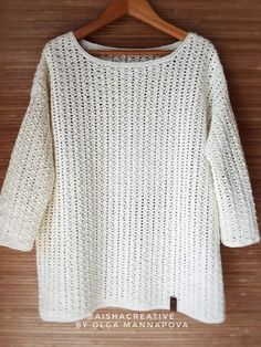 a white sweater hanging on a wooden hanger