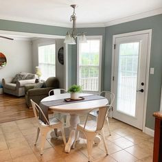 a dining room table and chairs in a living room with blue walls, wood floors and tile flooring