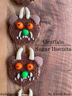 three decorated cookies on top of a wooden table with chocolate frosting and candy eyes