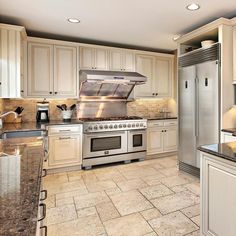 a large kitchen with white cabinets and stainless steel appliances, including an island countertop