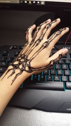 a person's hand on top of a computer keyboard with skeleton tattoos on it