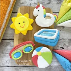 a wooden board topped with cookies shaped like beach items and toys on top of it