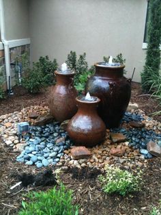 three brown vases sitting on top of a pile of rocks next to a building