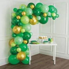 green and gold balloon arch in the corner of a room