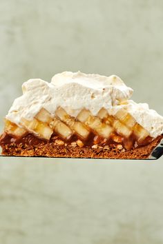 a piece of cake with bananas and whipped cream on top is being held up by a spatula