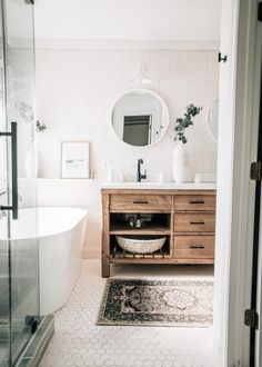 a bathroom with a sink, mirror and bathtub next to a rug on the floor