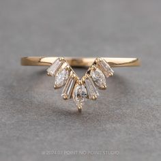 a yellow gold ring with three pear shaped diamonds on it's side, sitting on a gray surface