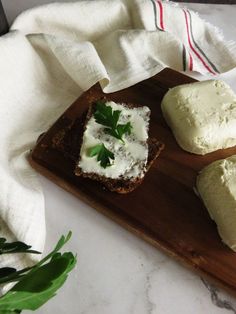 three pieces of bread with cheese and parsley on top sitting on a cutting board