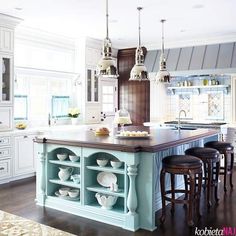 a large kitchen with an island in the middle and two stools at the end