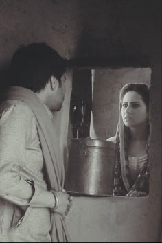 a man and woman standing in front of a mirror looking at each other while holding a pot