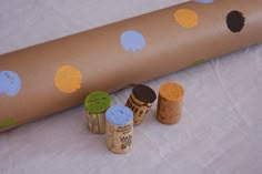 three corks are sitting next to a roll of brown paper with polka dots on it