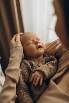 a woman holding a baby in her arms and looking at it's face with eyes closed