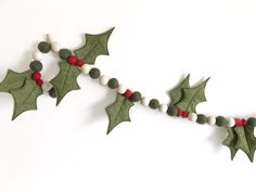 a garland with holly leaves and berries hanging from it's sides on a white wall