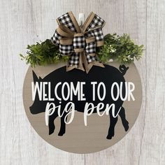 a welcome sign hanging on the side of a wooden wall with a pig in it