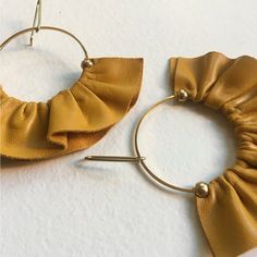 a pair of gold colored metal hoop earrings with large ruffles hanging from them