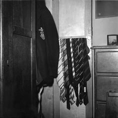 a black and white photo of ties hanging on a wall in a room with an armoire