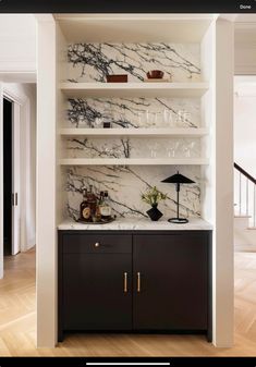 a white and black kitchen with marble counter tops, cabinets and shelves on the wall