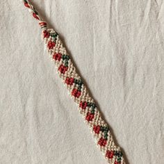 a close up of a bracelet on a white surface with red, green and blue beads