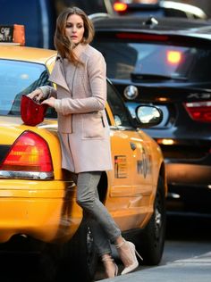 a woman walking across a street next to a taxi