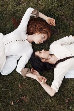 two women laying on the grass with their arms around each other