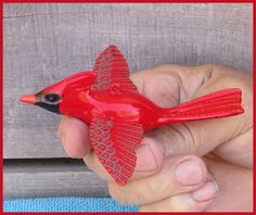 a hand holding a red bird shaped object