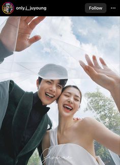 a man and woman are posing for a photo with their hands up in the air