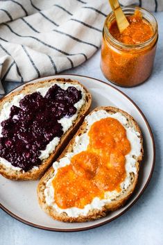 two pieces of bread on a plate with jam in the jar next to each other