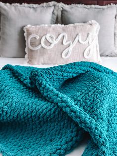 a crocheted blanket laying on top of a bed next to two pillow cases