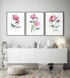 three pink flowers are hanging on the wall above a white cabinet and sideboard in a modern living room