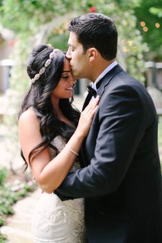 a bride and groom kissing in front of trees