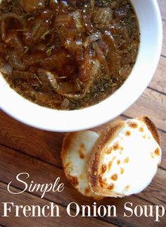 a bowl of french onion soup next to a baguette on a wooden table