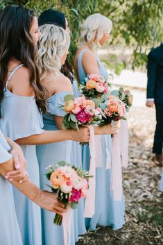 a group of women standing next to each other holding bouquets