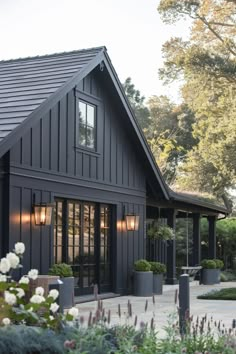 a black house with lots of windows and plants