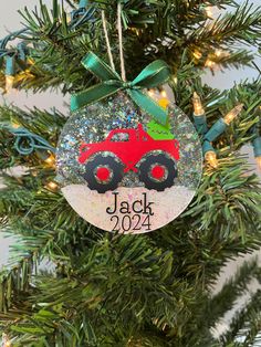 a christmas ornament with a red truck and green bow hanging from a tree