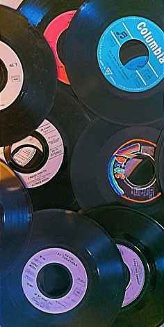 many different colored records are stacked on top of each other in a pile, one is black and the other is white