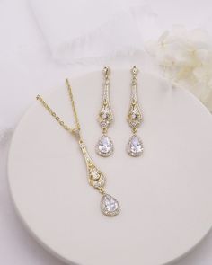 Complete your bridal look with this stunning wedding jewelry set. The sparkling cubic zirconia stones delicately accentuate the bride's natural beauty, adding a touch of elegance and glamor. Featuring an art deco style design, this bridal jewelry set features CZ teardrops accented with a filigree pattern. DETAILS * High quality cubic zirconia.  * Earrings measure 2 inches long. * Necklace is adjustable from 16 inches to 18 inches long, pendant (including bail) measures 2 inches. * Perfect for brides, bridesmaids, prom, or any special occasion. Optional custom cards available for gift giving! * Optional bracelet measures 7 inches long. * Finish: silver, gold or rose gold. * Hypoallergenic, lead-free & nickel-free. SHIPPING * Leaves our facility within 1-3 business days. * Shipping upgrades Dazzling Cubic Zirconia Bridal Earrings For Wedding, Elegant Crystal Bridal Sets For Marriage, White Cubic Zirconia Jewelry Sets With Matching Earrings, Elegant Bridal Sets For Marriage, Classic Cubic Zirconia Bridal Earrings For Wedding, Elegant Jewelry For Marriage With Matching Earrings, White Cubic Zirconia Bridal Accessories For Wedding, Diamond White Cubic Zirconia Jewelry Sets For Wedding, Crystal Bridal Necklace With Prong Setting For Wedding