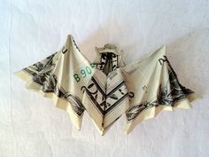 an origami bat hanging on the wall in front of a white background with black and green designs