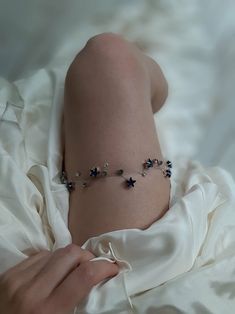 a woman laying on top of a bed wearing a white dress and bracelet with blue flowers