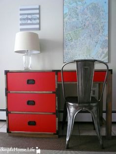 a metal chair sitting in front of a red chest of drawers with a map on the wall behind it