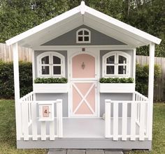 a small white and pink house sitting in the grass