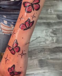 a woman's arm with pink and black butterflies tattooed on the back of it