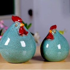 two ceramic chickens sitting next to each other on a table