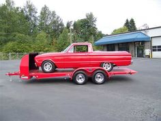 an old red truck is parked in a parking lot with its door open and it's flatbed