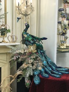 a peacock statue sitting on top of a table next to a fire place and chandelier