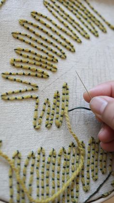 someone is stitching something on a piece of fabric with needle and thread in front of it