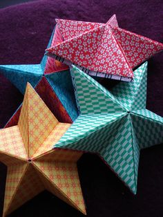 four origami stars sitting on top of a purple surface with one folded in half