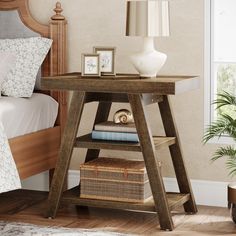 a small wooden table with some books and pictures on it next to a bed in a room