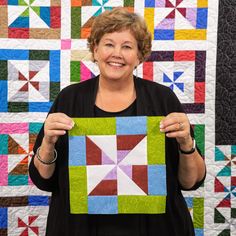 a woman holding up a piece of quilt