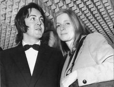 a man and woman standing next to each other in front of a wall with letters on it